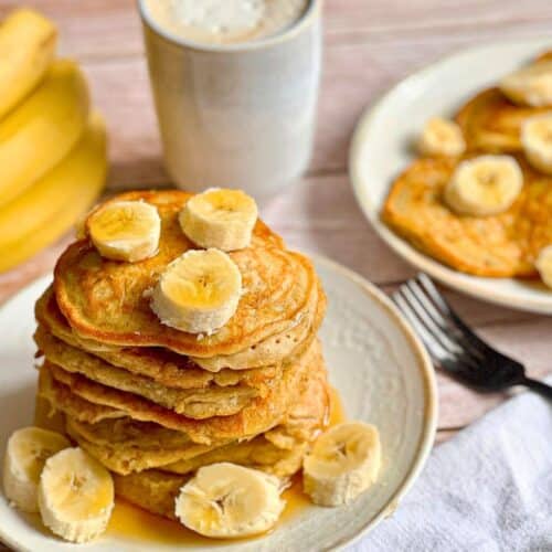 Vegane Bananen-Pancakes mit Ahornsirup gestapelt auf einem Teller.