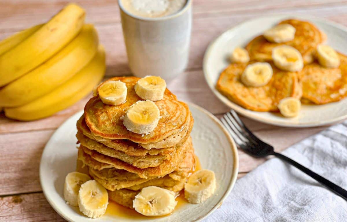 Vegane Bananen-Pancakes mit Ahornsirup gestapelt auf einem Teller.
