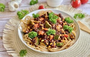 Vegane Beluga-Bolognese mit Gemüse und Spaghetti auf einem Teller.