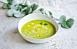 Vegane Erbsensuppe mit Kokosmilch, Minze, Sesam und Lauchzwiebeln in einem Suppenteller.