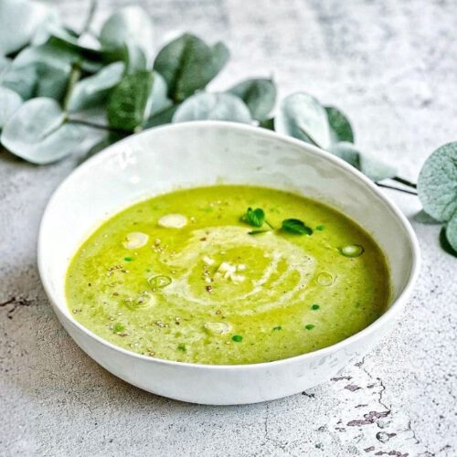 Vegane Erbsensuppe mit Kokosmilch, Minze, Sesam und Lauchzwiebeln in einem Suppenteller.