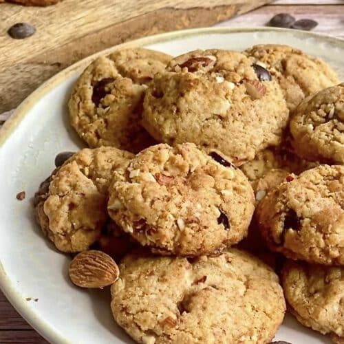 Vegane Erdnussbutter-Kekse mit Mandelbruch und Schokostückchen auf einem Teller.