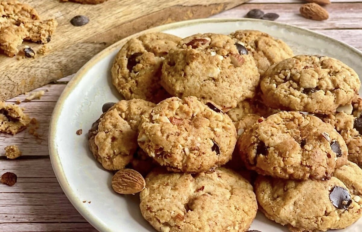 Vegane Erdnussbutter-Kekse mit Mandelbruch und Schokostückchen auf einem Teller.