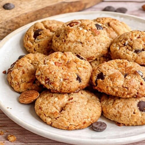 Vegane Erdnussbutter-Kekse mit Mandeln und Schokolade auf einem Teller.