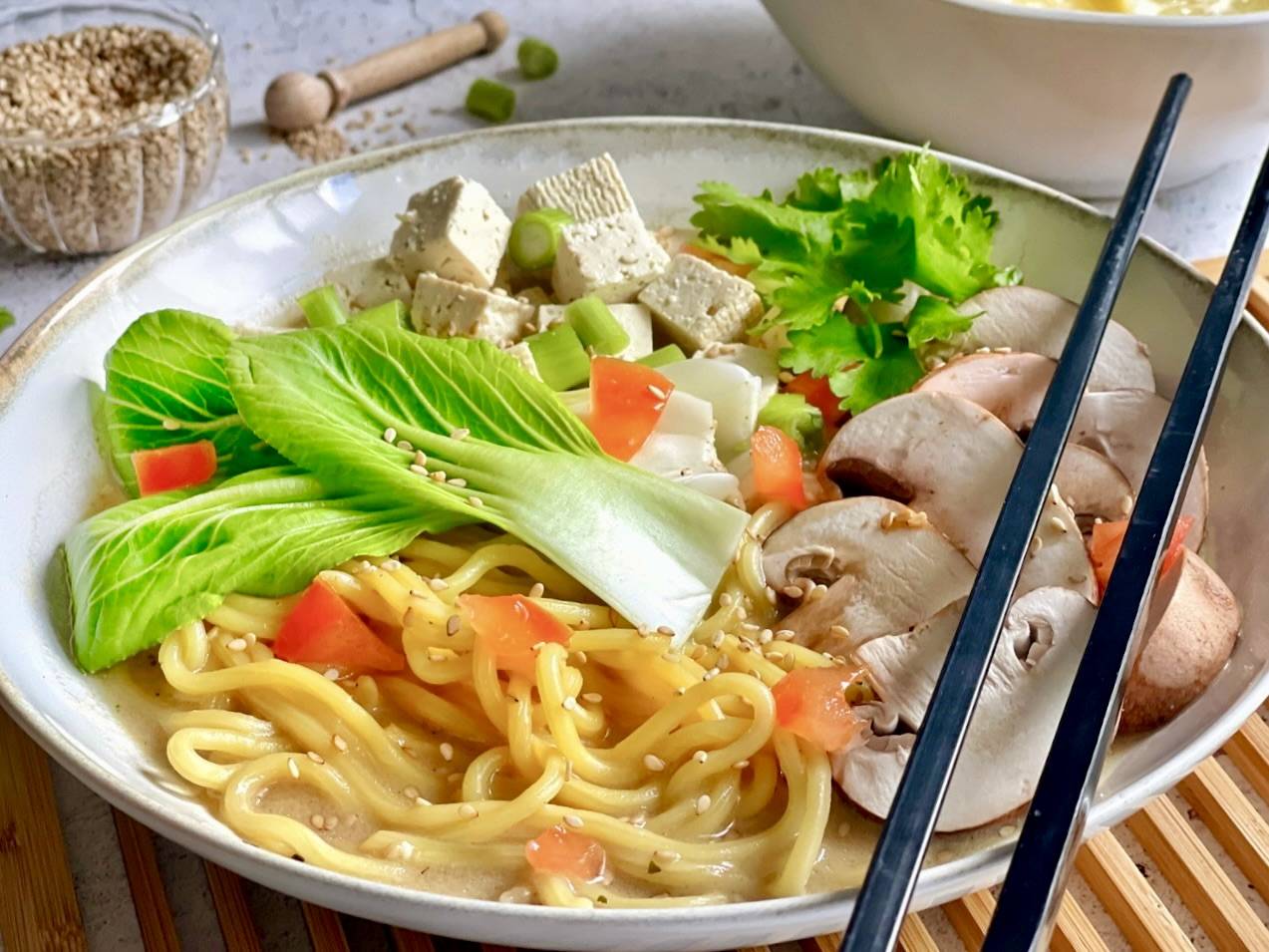 Vegane Misosuppe mit Tofu, Pak Choi, Champignons und Nudeln in einer Schüssel.