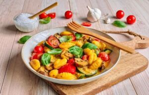 Vegane Gnocchi-Gemüsepfanne mit Basilikum auf einem Teller.