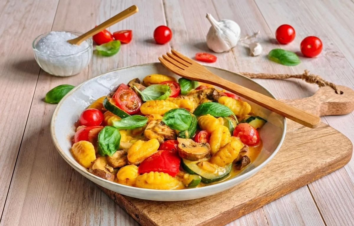 Vegane Gnocchi-Gemüsepfanne mit Basilikum auf einem Teller.
