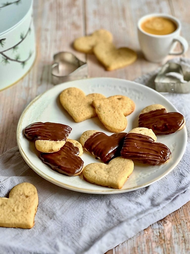 Vegane Ingwer-Zitronen-Kekse, teilweise mit Schokoladentopping, auf einem Teller.