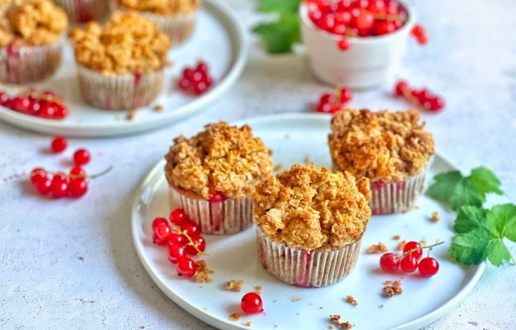Vegane Johannisbeermuffins mit Streuseln auf Tellern.