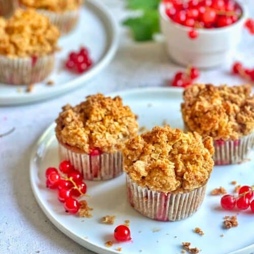 Vegane Johannisbeermuffins mit Streuseln auf Tellern.