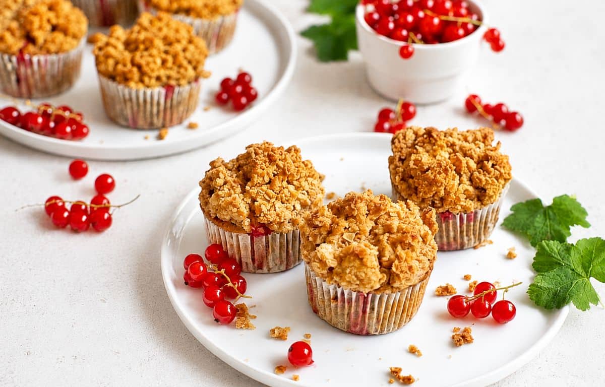 Vegane Johannisbeermuffins mit Streuseln auf Tellern.