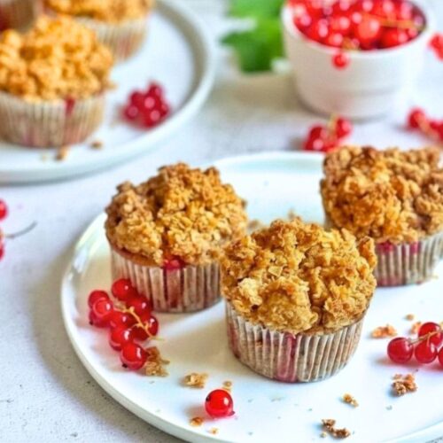 Vegane Johannisbeermuffins mit Streuseln auf Tellern.