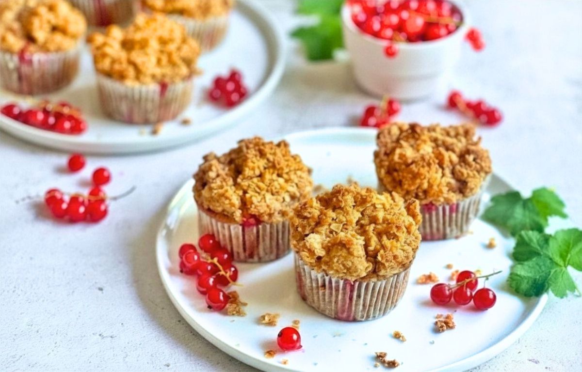 Vegane Johannisbeermuffins mit Streuseln auf Tellern.