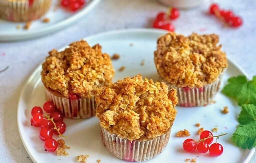 Vegane Johannisbeermuffins mit Streuseln auf Tellern.