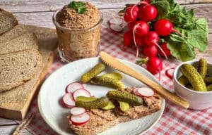 Vegane Leberwurst in einem Glas und auf zwei Broten auf einem Teller.