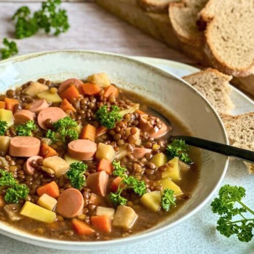 Vegane Linsensuppe mit Würstchen in einem Suppenteller.