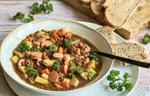 Vegane Linsensuppe mit Würstchen in einem Suppenteller.