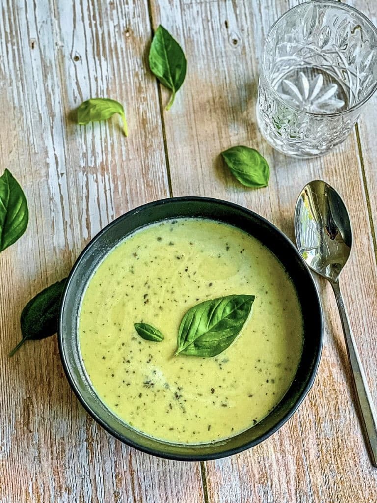 Leckere vegane Zucchinisuppe mit Basilikum in einem Suppenteller.