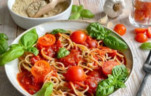 Pasta mit Tomatensoße und Basilikum auf einem Teller.