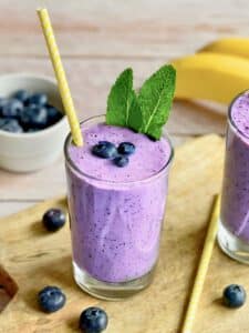 Veganer Blaubeeren-Bananen-Shake in zwei Gläsern mit Minze dekoriert.