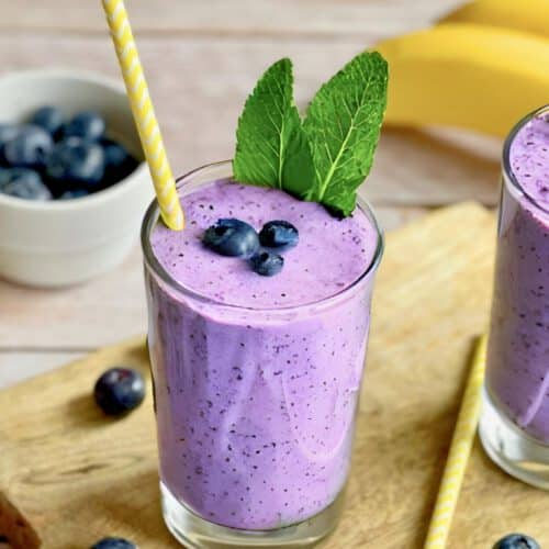 Veganer Blaubeeren-Bananen-Shake in zwei Gläsern mit Minze dekoriert.