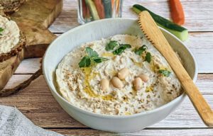 Veganer cremiger Bohnenaufstrich in einer Schüssel mit Rohkoststicks und Vollkornbrot.