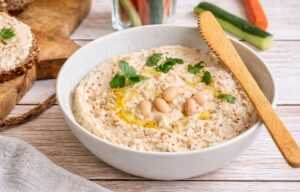 Veganer Bohnenaufstrich in einer Schüssel mit Rohkoststicks und Vollkornbrot.