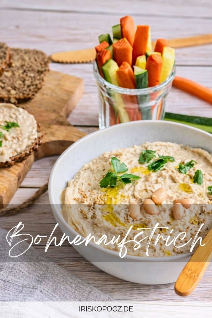 Veganer Bohnendip in einer Schüssel mit Rohkoststicks und Vollkornbrot-Pin.