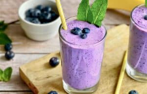 Veganer Blaubeeren-Bananen-Shake in zwei Gläsern mit Minze dekoriert.