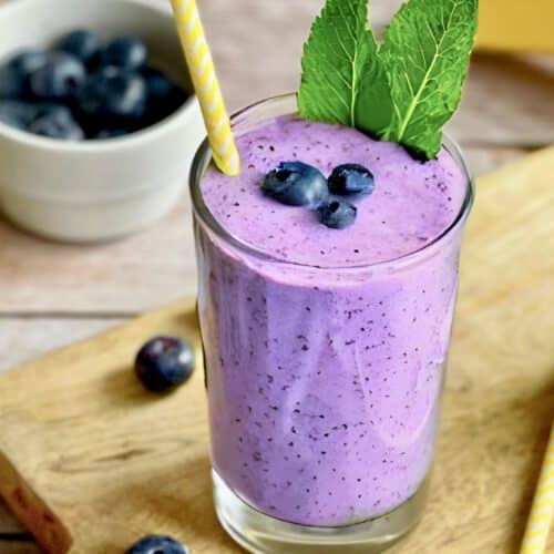 Veganer Blaubeeren-Bananen-Shake in zwei Gläsern mit Minze dekoriert.
