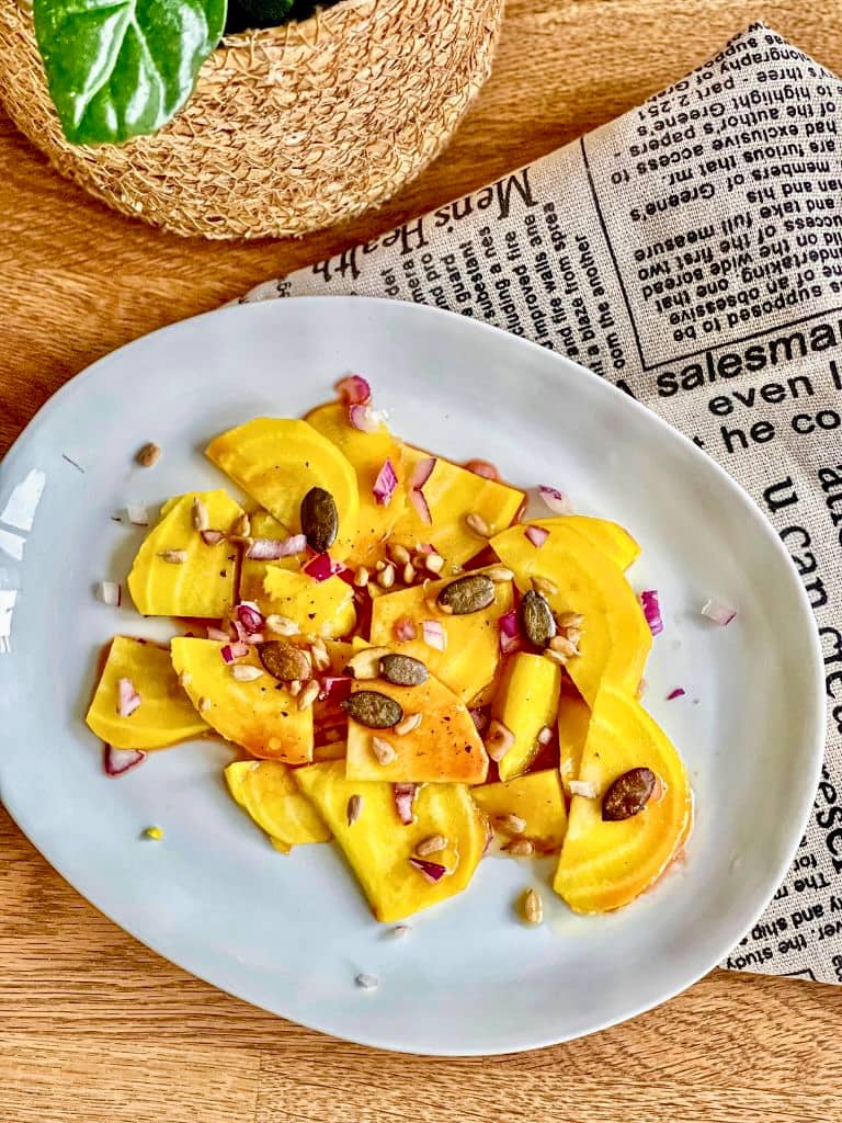 Gelbe-Bete-Salat mit Kerntopping auf einem Teller.