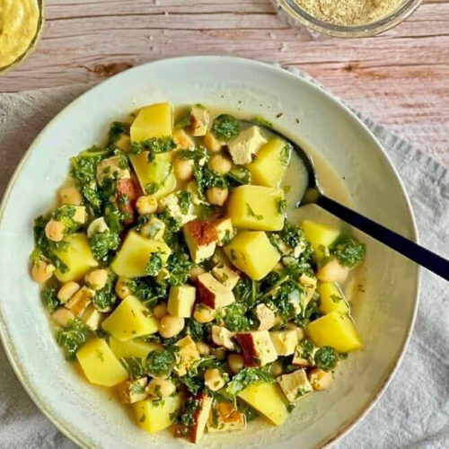Veganer Kartoffel-Grünkohl-Eintopf mit Räuchertofu und Kichererbsen in einem Suppenteller.