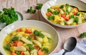 Veganer Mairübchen-Eintopf mit Gemüse, Kartoffeln, Räuchertofu und Petersilie in Suppentellern.