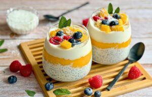 Mango-Chiapudding mit Kokos im Glas auf einem Holztisch.