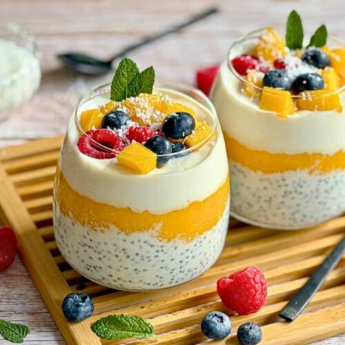 Mango-Chiapudding mit Kokos im Glas auf einem Holztisch.