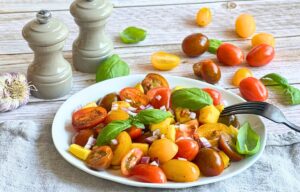 Veganer Tomaten-Mango-Salat mit Basilikum auf einem Teller.