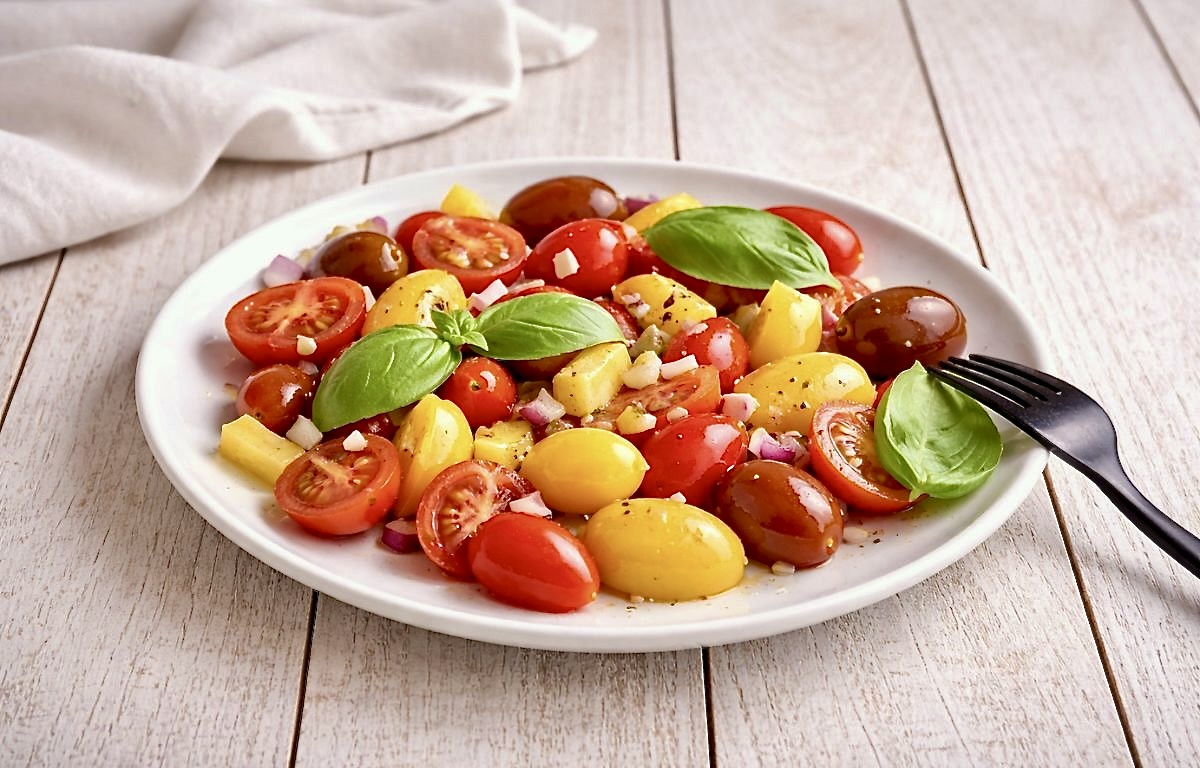 Tomaten-Mango-Salat mit Basilikum auf einem Teller.