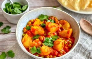 Aloo Matar: Ein herzhaftes indisches Curry mit Kartoffeln und Erbsen auf einem Teller mit Naan-Brot.