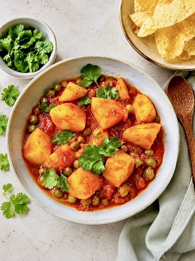 Aloo Matar: Ein veganes indisches Curry mit Kartoffeln und Erbsen auf einem Teller.