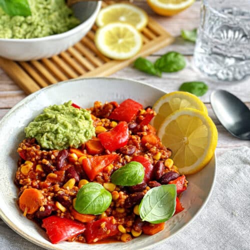 Veganes Chili sin Carne mit Buchweizen und Guacamole auf einem Teller.