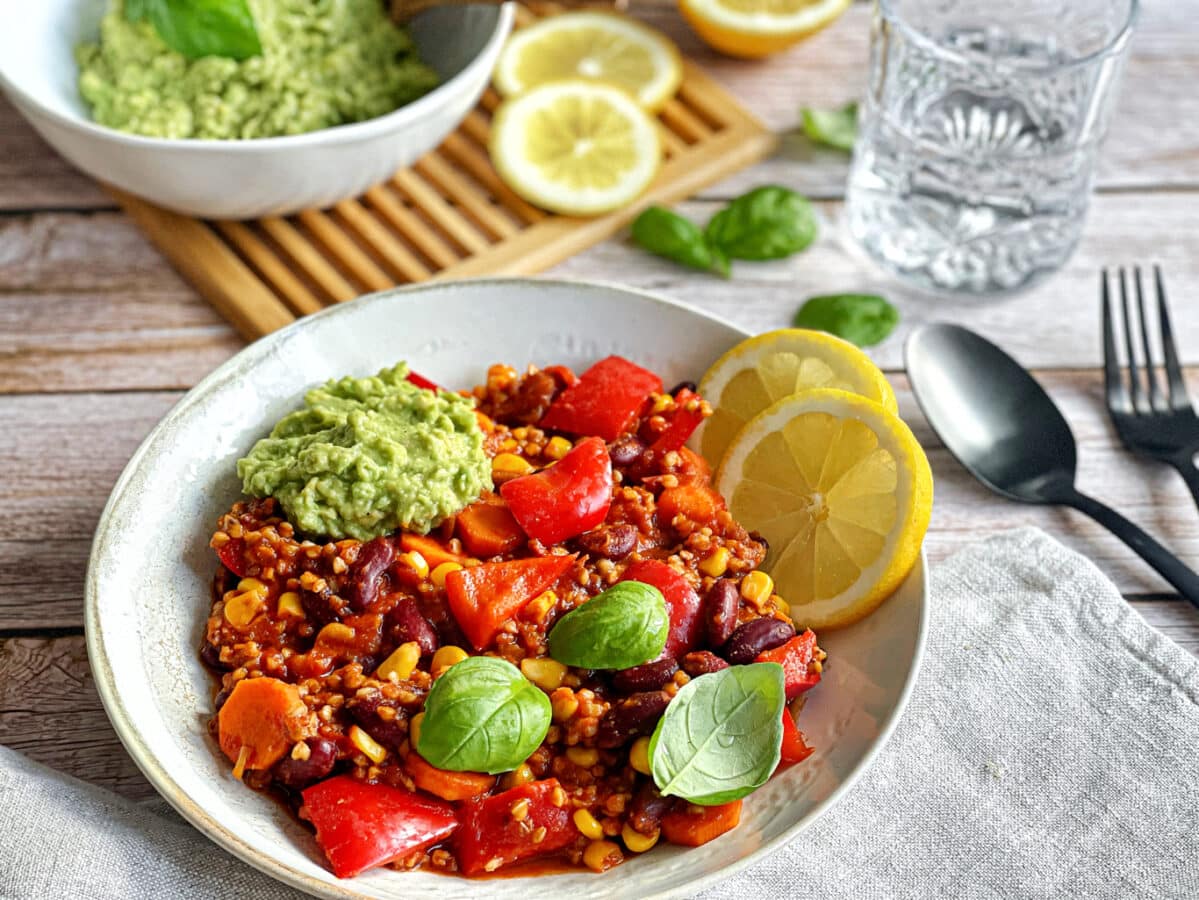 Veganes Chili sin Carne mit Buchweizen und Guacamole auf einem Teller.