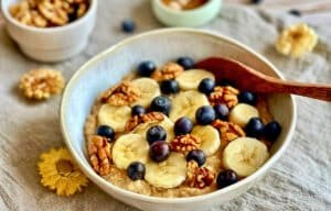 Veganes Porridge mit Banane, Zimt, Beeren und Nüssen in einer Schüssel.