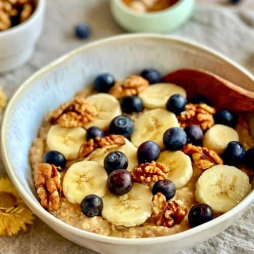 Veganes Porridge mit Banane, Zimt, Beeren und Nüssen in einer Schüssel.