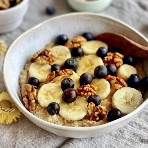 Veganes Porridge mit Banane, Zimt, Beeren und Nüssen in einer Schüssel.