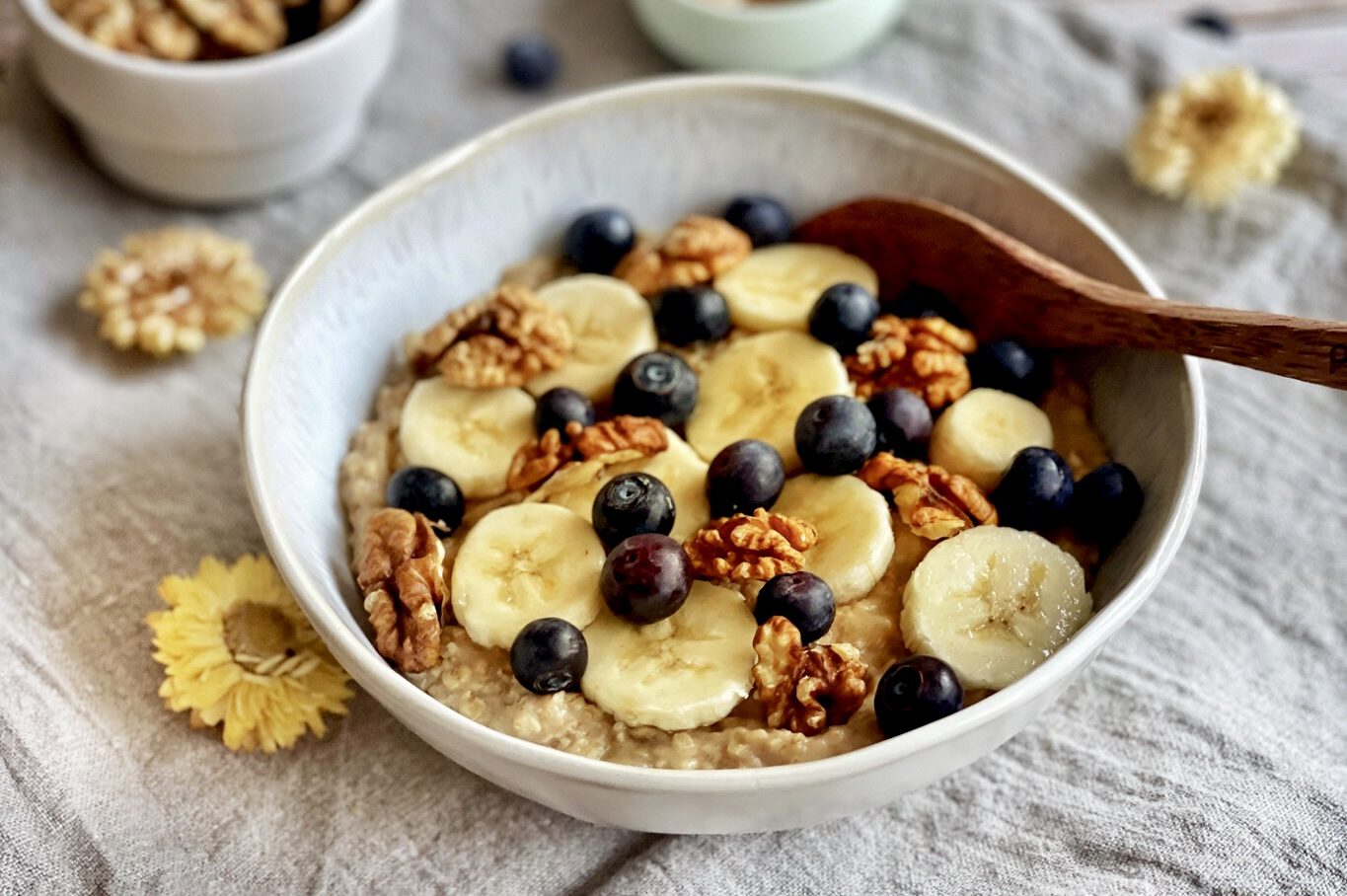 Veganes Porridge mit Banane, Zimt, Beeren und Nüssen in einer Schüssel.