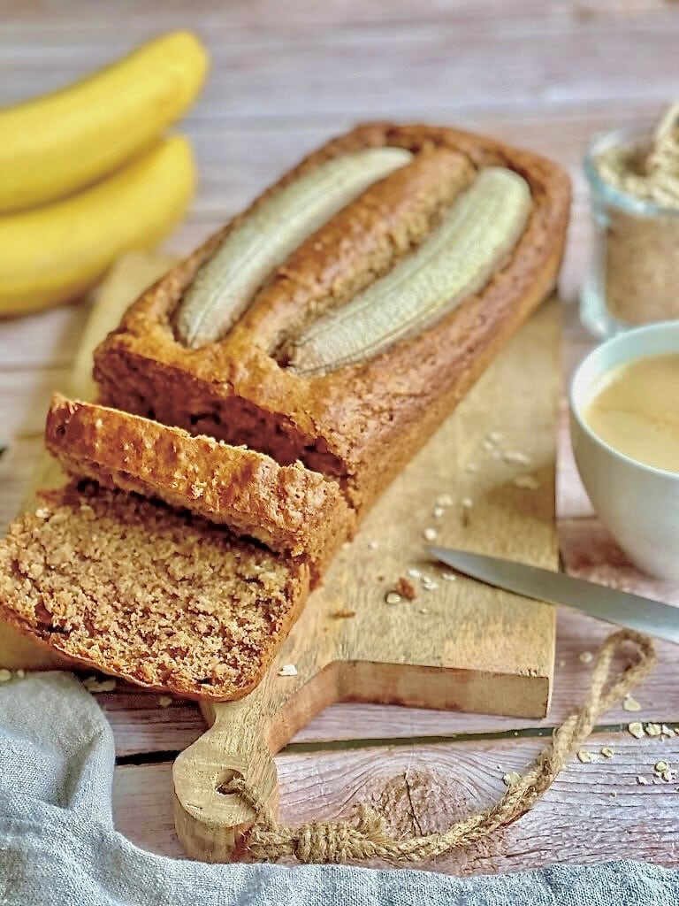 Veganes Bananenbrot mit Haferflocken auf einem Holzbrett.